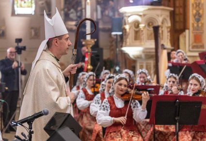 Zbliżenie na Biskupa w trakcie Mszy, który za chwilę będzie udzielał sakramentu Bierzmowania młodzieży, w tle widoczna część orkiestry w kostiumach wilanowskich