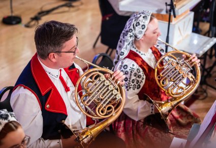 Zbliżenie na dwóch Muzyków z Orkiestry w kostiumach wilanowskich grających na waltorni