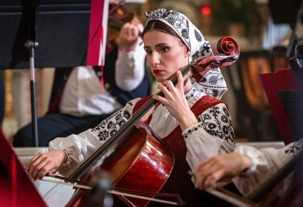 Zbliżenie na Muzyczkę w kostiumie wilanowskim w trakcie gry na instrumencie smyczkowym