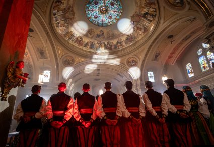 Widok zza pleców Artystów Chóru w kostiumach łowickich na kopułę z witrażem sufitowym