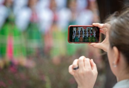 Zbliżenie na moment nagrywania koncertu telefonem przez Kobietę z publiczności