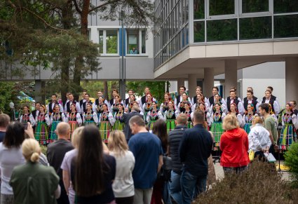 Artyści chóru w kostiumach łowickich a przed nimi Publiczność
