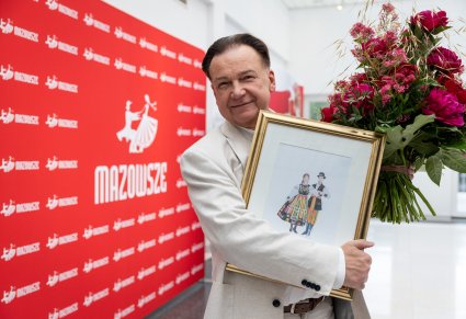 Zbliżenie na Marszałka Województwa Mazowieckiego, który trzyma akwarelę oraz bukiet kwiatów