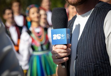 Zbliżenie na mikrofon dziennikarza TVN24, z logo urodzinowym 25 lat TVN24