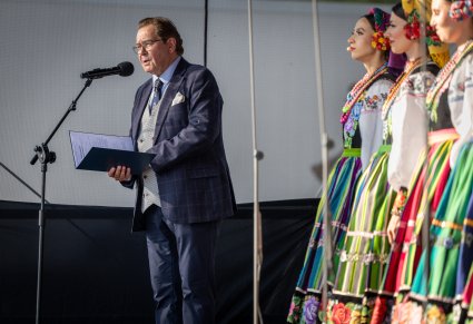 Konferansjer podczas przemowienia w trakcie koncertu, obok widoczna część chóru