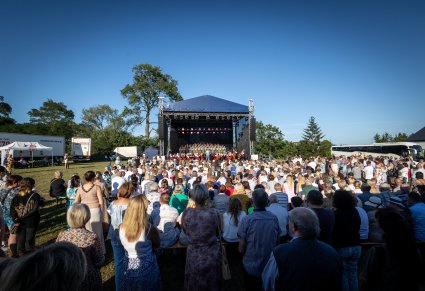 Daleki widok na scenę z chórem i orkiestrą, z perspektywy publiczności