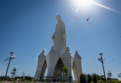 Pomnik Matki Boskiej w całości, w tle helikopter wypuszczający płatki róż