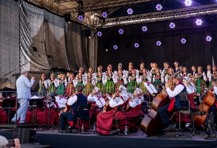 Orkiestra wraz z dyrygujacycm Dyrektorem zespołu oraz chór na scenie podczas koncertu