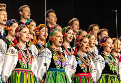 Zbliżenie na Artystów Chóru w kostiumach łowickich podczas śpiewu