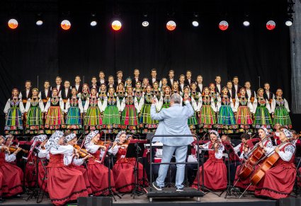 Na pierwszym planie Dyrygent zwrócony w stronę Orkiestry i chóru