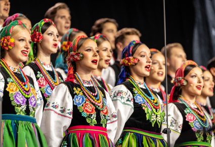 Zbliżenie na Artystów chóru w kostiumach łowickich w trakcie śpiewu