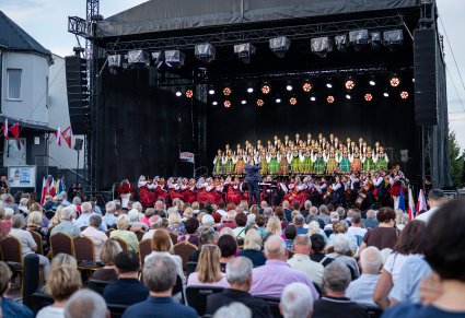 Widok na scenę na której znajduje się Dyrygent, Orkiestra w kostiumach wilanowskich i chór w kostiumach łowickich