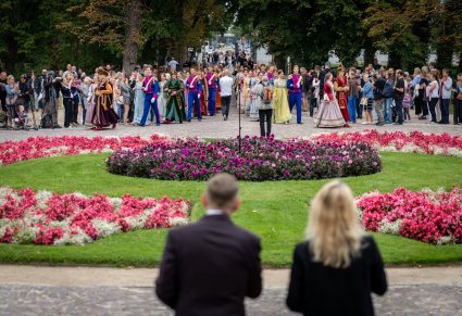 Widok na Artystów w kontuszach i kostiumach Księstwa Warszawskiego zmierzających pod Pałac Myślewicki, aby wspólnie z Publicznością zatańczyć Poloneza
