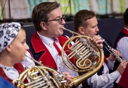 Zbliżenie na Artystów Orkiestry w kostiumach wilanowskich w trakcie gry na instrumentach dętych