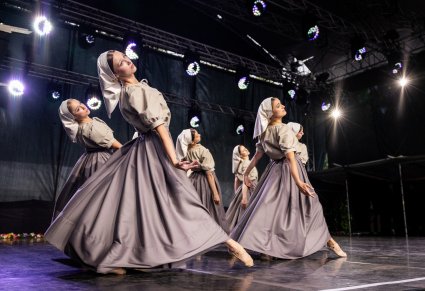 Zbliżenie na Artystki Baletu w stylizowanych, szarych kostiumach w trakcie wykonywania choreografii tanecznej