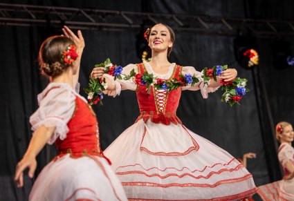 Zbliżenie na Artystki Baletu w kostiumach stylizowanych w trakcie wykonywania choreografii tanecznej z wykorzystaniem elementów scenogfrafii