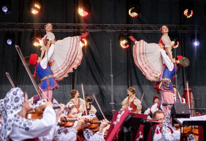 Na scenie widoczne dwie pary Artystów w kostiumach stylizowanych w trakcie wykonywania choreografii tanecznej, niżej widoczna część Orkiestry w kostiumach wilanowskich