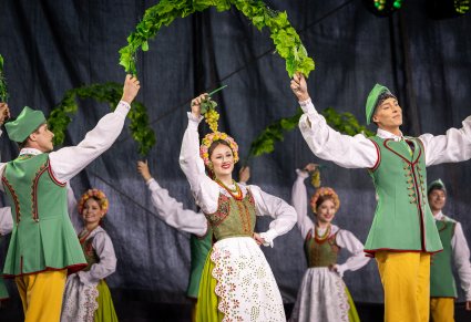 Widok na Artystów w kostiumach lubuskich w trakcie wykonywania choreografii tanecznej wykorzystując elementy winorośla