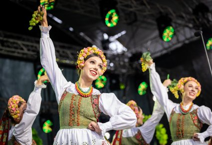 Zbliżenie na Artystki w kostiumach lubuskich w trakcie wykonywania choreografii tanecznej z wykorzystaniem elementów kiści winogrona