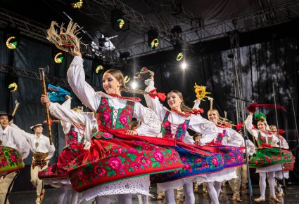 Na scenie Artyści w kostiumach podhalańskich w trakcie wykonywania choreografii tanecznej