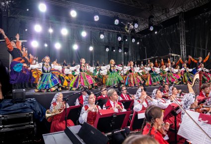 Widok na orkiestrę w kostiumach wilanowskich a na scenie wyżej Artyści w finałowej pozycji