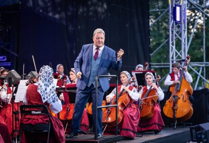 Na pierwszym planie dyrygujacy Dyrektor Zespołu, w tle orkiestra w kostiumach wilanowskich
