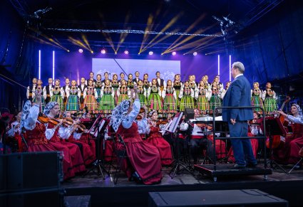 Chór w kostiumach łowickich, orkiestra w kostiumach wilanowskich i podhalańskich wraz z dyrygujacym Dyrektorem Zespołu
