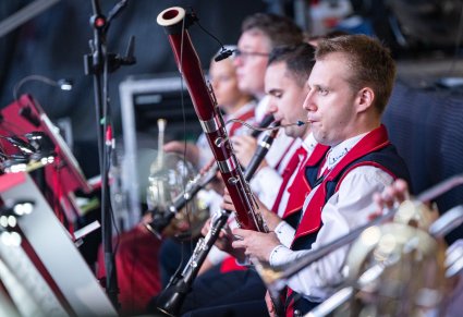Muzycy orkiesty w kostiumach wilanowskich, grający na instrumentach dętych, podczas koncertu