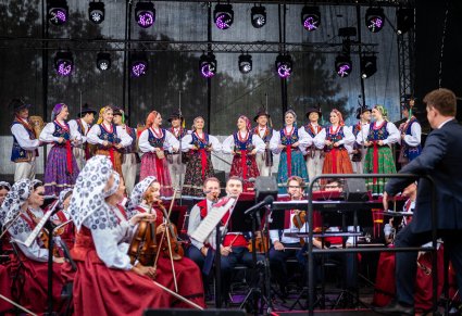 Na pierwszym planie Artyści orkiestry w kostiumach wilanowskich wraz z Dyrygentem, a na drugim planie grupa Artystów w kostiumach limanowskich