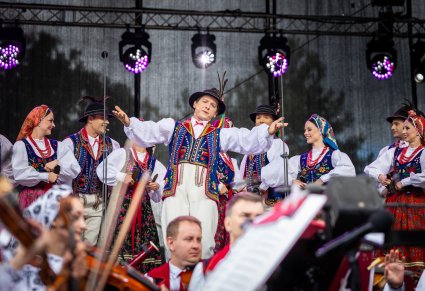 Grupa Artystów w kostiumach limanowskich w trakcie wykonywania śpiewu i choreografii tanecznej
