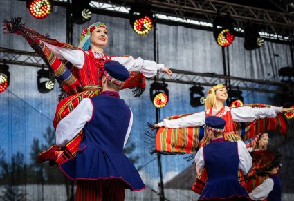 Pary Artystów w kostiumach sieradzkich w trakcie wykonywania choreografii tanecznej
