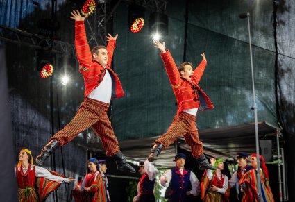 Na pierwszym planie dwóch Artystów Baletu w kostiumach sieradzkich w trakcie wykonywania choreografii tanecznej