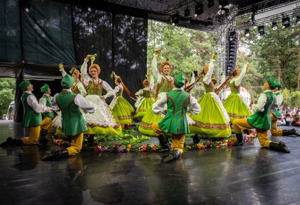 Grupa Artystów w kostumach lubuskich w trakcie wykonywania choreografii tanecznej z wykorzystaniem elementów imitujących winorośla