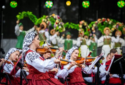 Na pierwszym planie Skrzypaczki w kostiumach wilanowskich w trakcie gry na skrzypcach, na drugim planie Artyści w kostiumach lubuskich w trakcie wykonywania choreografii tanecznej