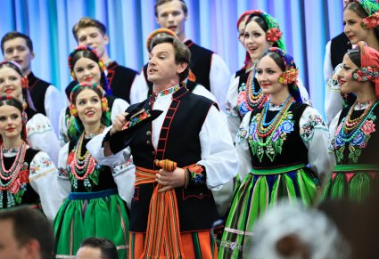Solista chóru, za nim widoczna część chóru, wszyscy w kostiuach łowickich