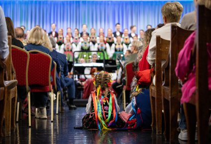 Zbliżenie na dziewczynkę w kostiumie krakowskim, ogladajacą koncert chóru