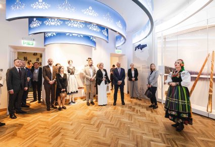 Przewodniczka w kostiumie łowickim wraz z uczestnikami Konwentu Przewodniczących Sejmików Województw RP podczas zwiedzania wystawy stałej w Centrum Folkloru Polskiego "Karolin"