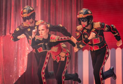 Zbliżenie na trójkę Artystów w kostiumach czarno czerwono złotych, wykonujący choreografię taneczną