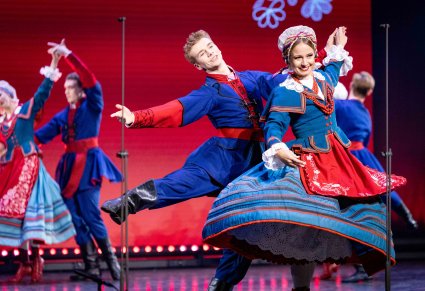 Pary Artystów w kostiumach kujawskich w trakcie wykonywania choreografii tanecznej na scenie