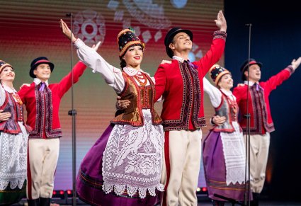 Trzy Pary Artystów w kostiumach kurpiowskich w trakcie wykonywania choreografii tanecznej