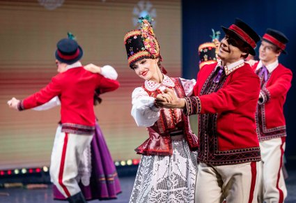 Zbliżenie na pary Artystów w kostiumach kurpiowskich w trakcie wykonywania choreografii tanecznej