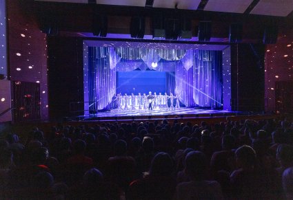 Widok na publiczność i scenę, na której znajdują się Artyści, którzy odgrywają rolę Księżyca i gwiazd.  Wysoko nad sceną wisi dyskotekowa kula, która oddaje wspaniałe światło