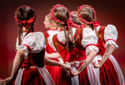 Kadr na grupę Artystek zwróconych do obiektywu tyłem, widoczne detale kostiumu jurgowskiego, takie jak wianki i kokardy na warkoczach