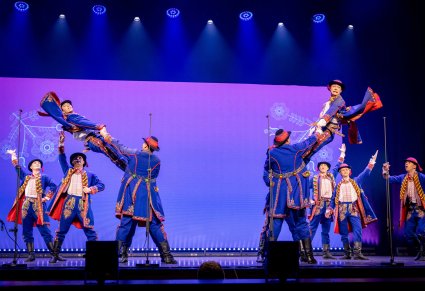 Grupa Artystów w kostiumach podegrodzkich w trakcie wykonywania choreografii tanecznej