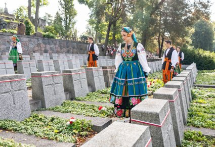 Artyści w kostiumach łowickich między grobami poległych na Cmentarzu na Rossie
