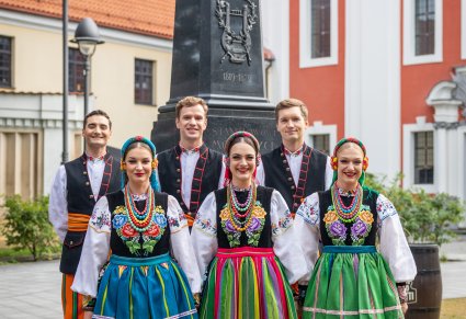 Trzy pary Artystów w kostiumach łowickich na skwerze kościoła św. Katarzyny przed pomnikiem Stanisława Moniuszki