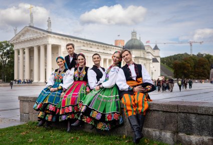 Trzy pary Artystów w kostiumach łowickim a w tle monumentalna Bazylika archikatedralna św. Stanisława Biskupa i św. Władysława