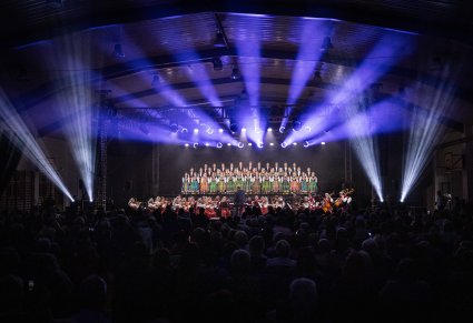 Widok na pięknie oświetloną scenę z Dyrygentem, Orkiestrą w kostiumach wilanowskich i Artystami Chóru w kostiumach łowickich