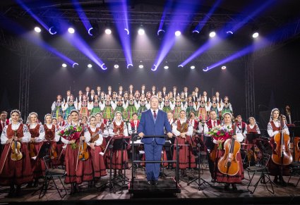 Na pierwszym planie Dyrektor zespołu, za nim Artyści Orkiestry w kostiumach wilanowskich, a wyżej na scenie Artyści Chóru w kostiumach łowickich