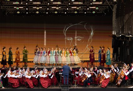 Widok na scenę na której znajduje się Dyrygent, Orkiestra w kostiumach wilanowskich, Artyści Baletu w kontuszach w trakcie wykonywania choreografii tanecznej